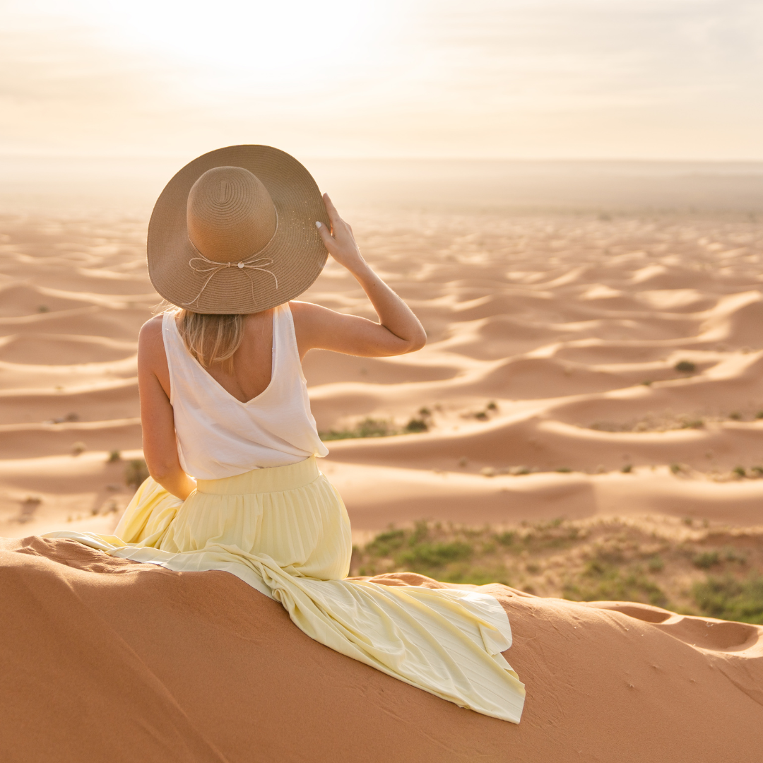 Femme assise sur une dune de sable au coucher du soleil, respirant calmement les yeux fermés — Méditation et apaisement mental