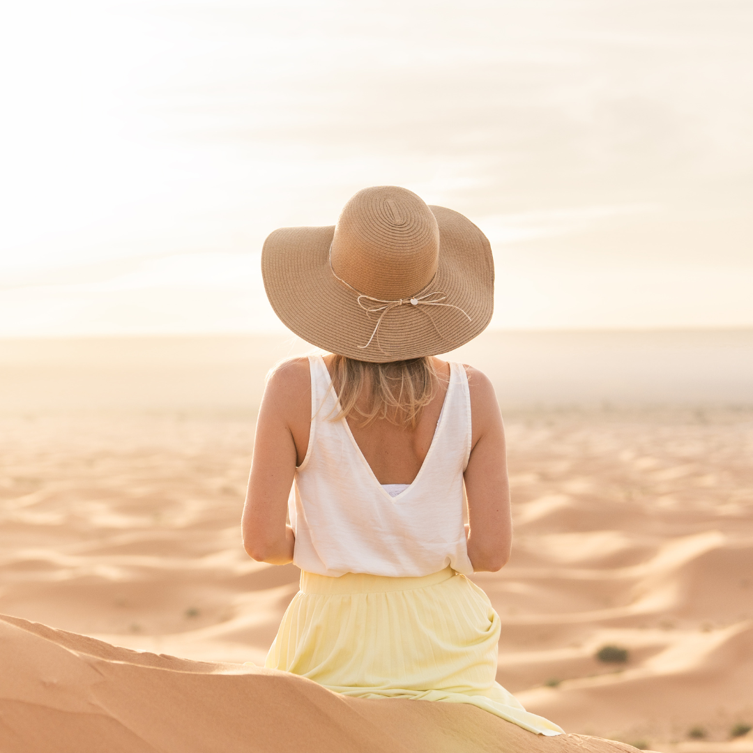 Femme assise sur une dune de sable au coucher du soleil, respirant calmement les yeux fermés — Méditation et apaisement mental