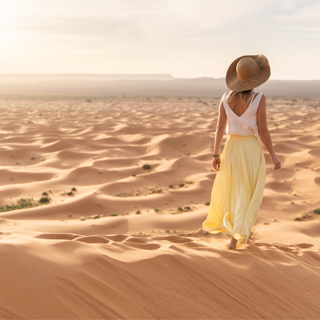 Femme assise sur une dune de sable au coucher du soleil, respirant calmement les yeux fermés — Méditation et apaisement mental