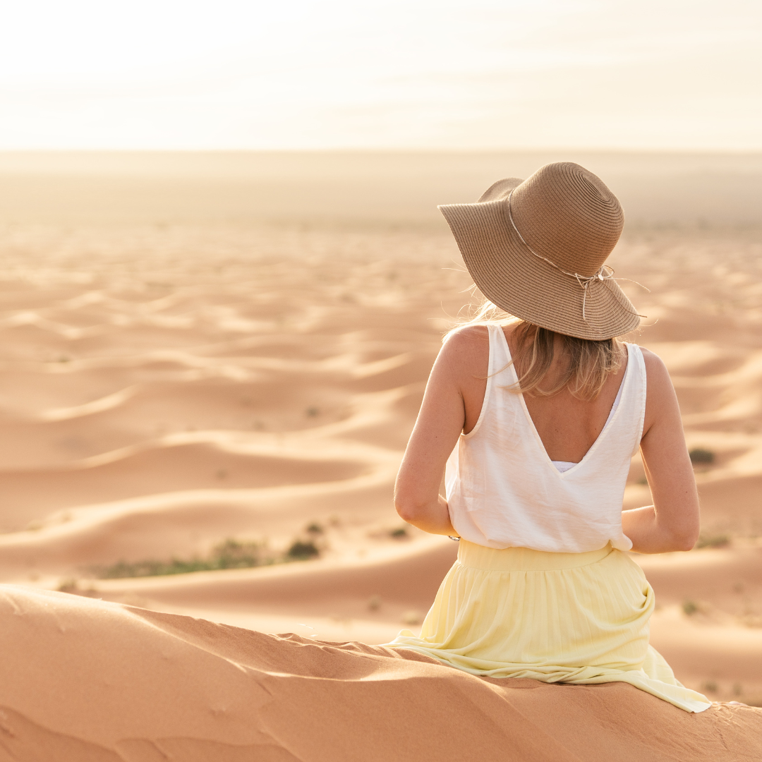 Femme assise sur une dune de sable au coucher du soleil, respirant calmement les yeux fermés — Méditation et apaisement mental